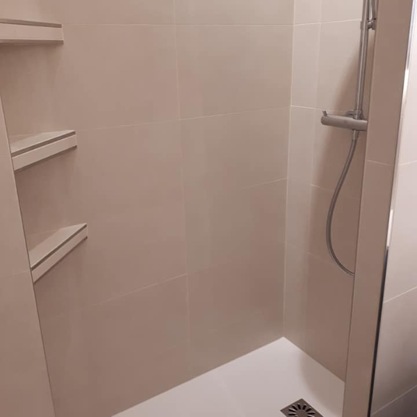 Douche italienne avec carrelage beige et étagères intégrées